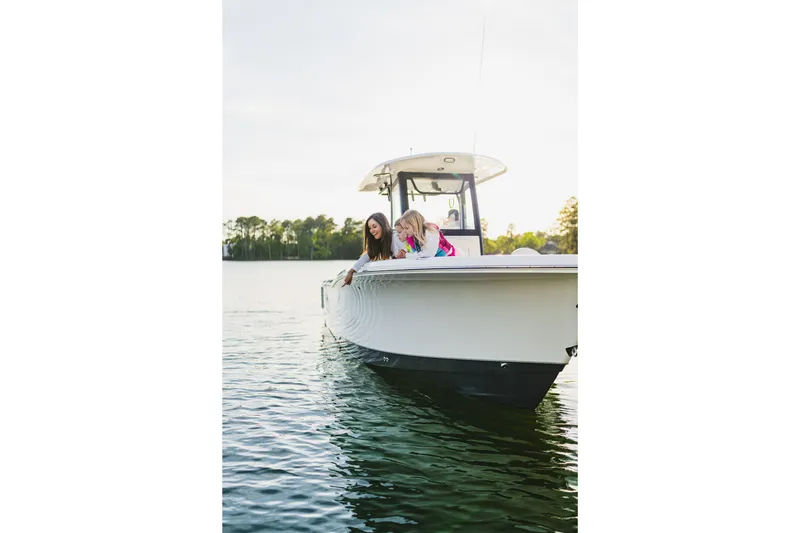 Slide: The Image of 2027 Sea Hunt Ultra 265SE boat on calm water with two people enjoying the view. - 35