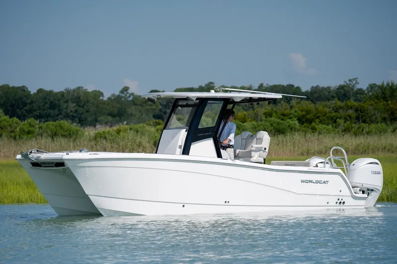 The Image of 2026 World Cat 265 CC-X boat cruising on calm water with lush greenery in the background. - 0