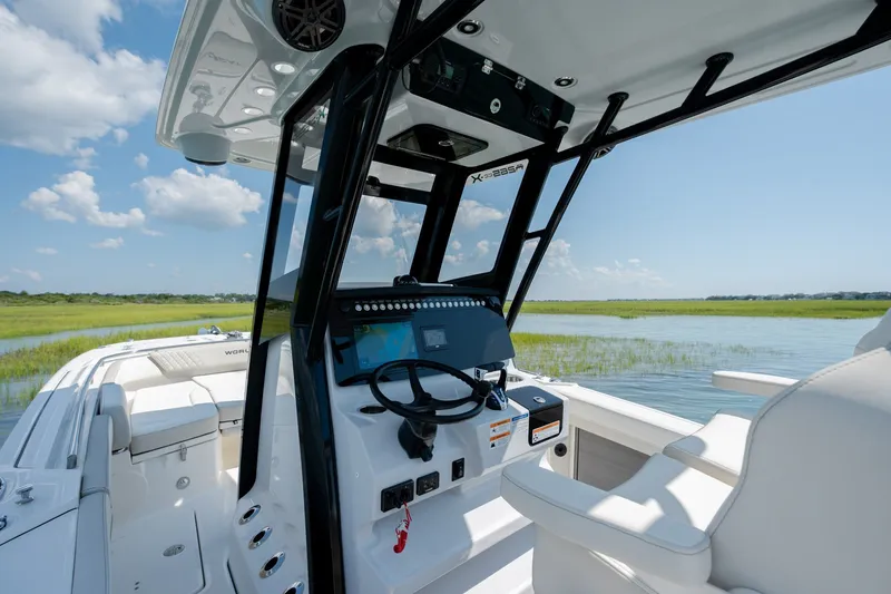 Slide: The Image of 2026 World Cat 265 CC-X boat interior with steering console, set against a serene water landscape. - 23