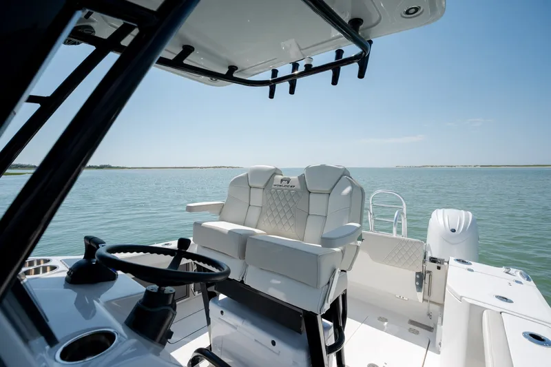 Slide: The Image of 2026 World Cat 265 CC-X boat interior with steering wheel and seating on calm water. - 21