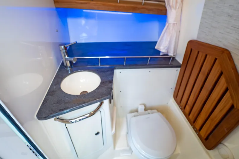 Slide: The Image of 2019 Boston Whaler 350 Realm bathroom with sink, toilet, and wooden accents. - 32