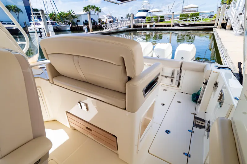 Slide: The Image of 2019 Boston Whaler 350 Realm boat interior with beige seating at marina. - 97