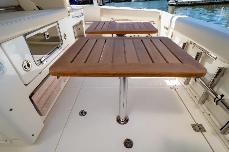 Slide: The Image of 2019 Boston Whaler 350 Realm boat interior with wooden tables and seating area. - 74