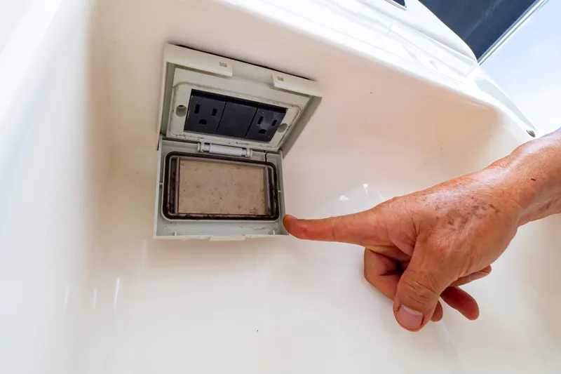 Slide: The Image of Boat electrical outlet on 2019 Boston Whaler 350 Realm, with hand pointing. - 91