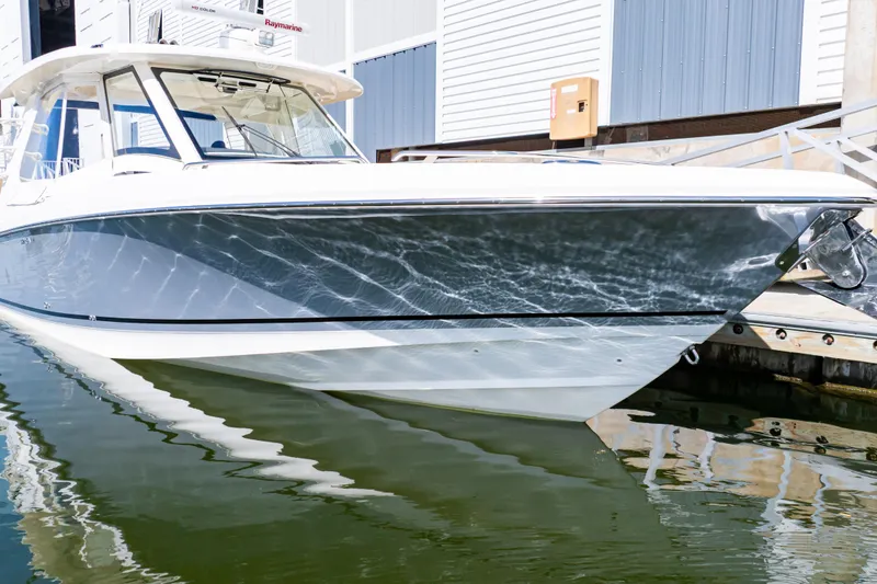 Slide: The Image of 2019 Boston Whaler 350 Realm boat docked, reflecting sunlight on water. - 22