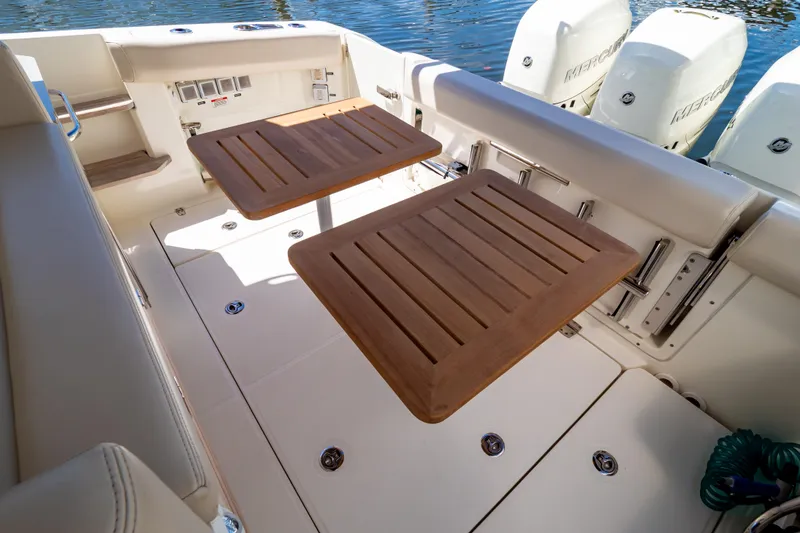Slide: The Image of 2019 Boston Whaler 350 Realm boat deck with wooden tables and Mercury engines. - 73