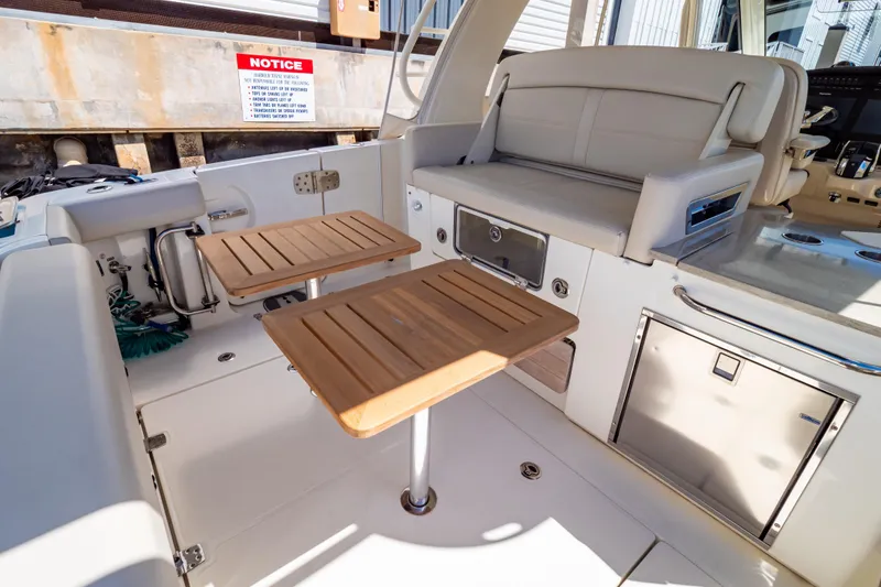 Slide: The Image of 2019 Boston Whaler 350 Realm interior with wooden tables and seating area. - 76