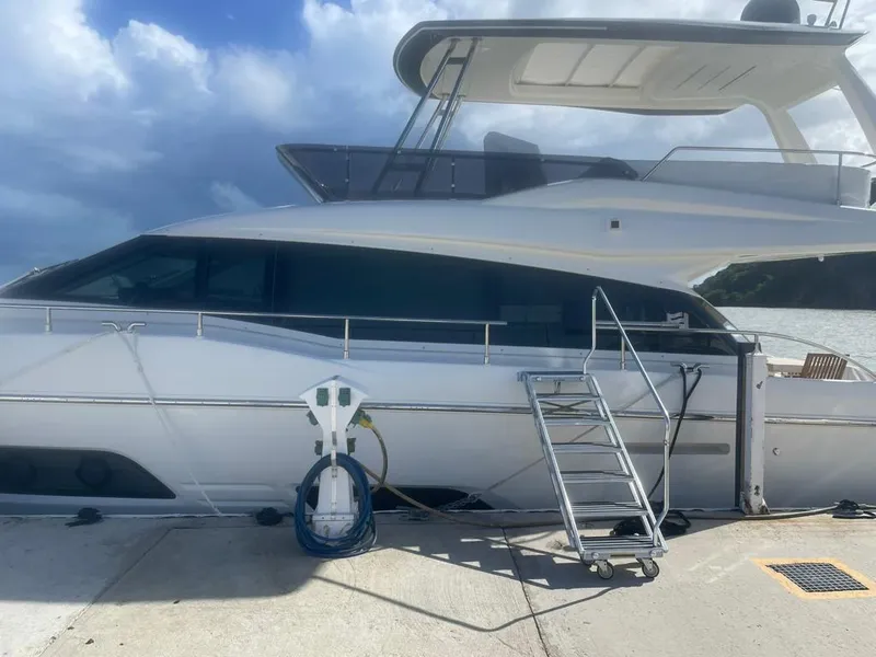 Slide: The Image of 2016 Ferretti Yachts 550 docked, side view with boarding ladder and blue sky background. - 3