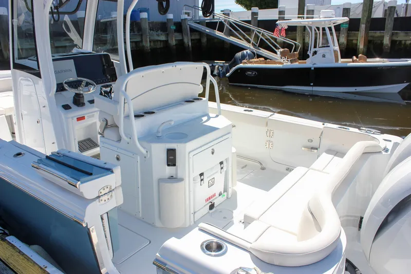 Slide: The Image of 2027 Sea Hunt Ultra 265SE boat interior with seating and control panel at dock. - 3