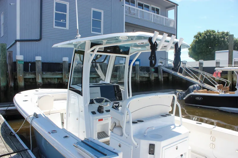 Slide: The Image of 2027 Sea Hunt Ultra 265SE boat docked near a waterfront building. - 2