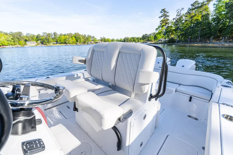 Slide: The Image of 2027 Sea Hunt Ultra 265SE boat interior with plush seating on a serene lake. - 63