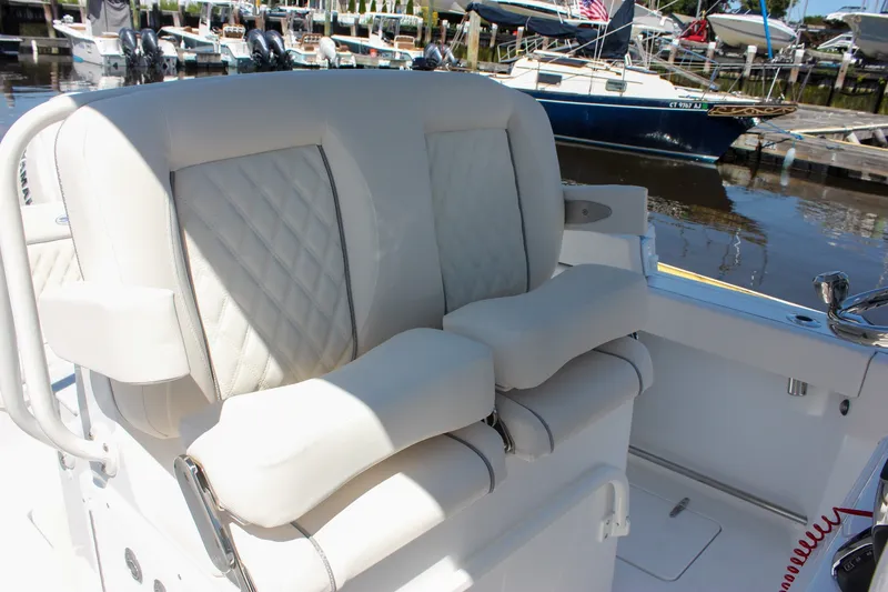 Slide: The Image of 2027 Sea Hunt Ultra 265SE boat with luxurious white seating at a marina. - 23