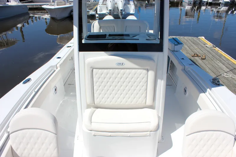 Slide: The Image of 2027 Sea Hunt Ultra 265SE boat interior with white seating at a marina. - 38