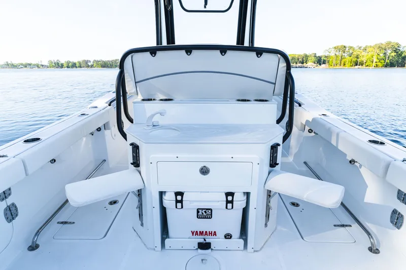 Slide: The Image of 2027 Sea Hunt Ultra 265SE boat interior with seating and storage, on calm water. - 62