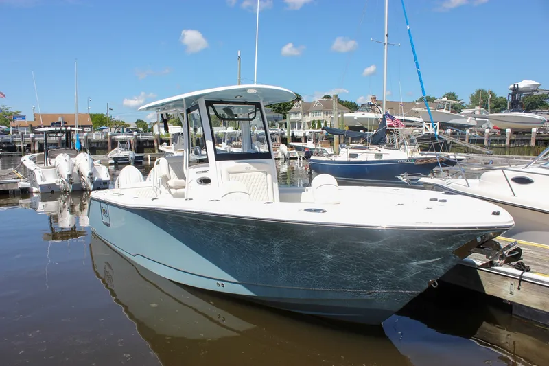 Slide: The Image of 2027 Sea Hunt Ultra 265SE boat docked in a marina under a clear blue sky. - 50