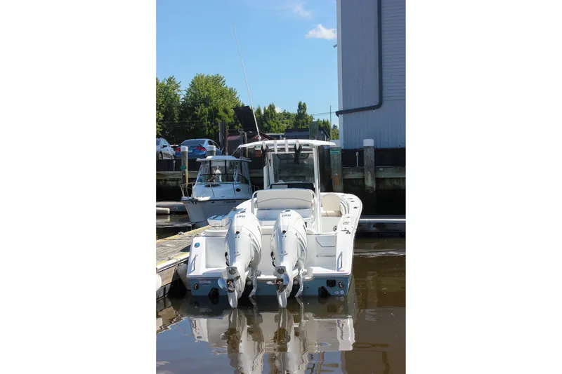 Slide: The Image of 2027 Sea Hunt Ultra 265SE boat docked with dual engines, reflecting on calm water. - 55
