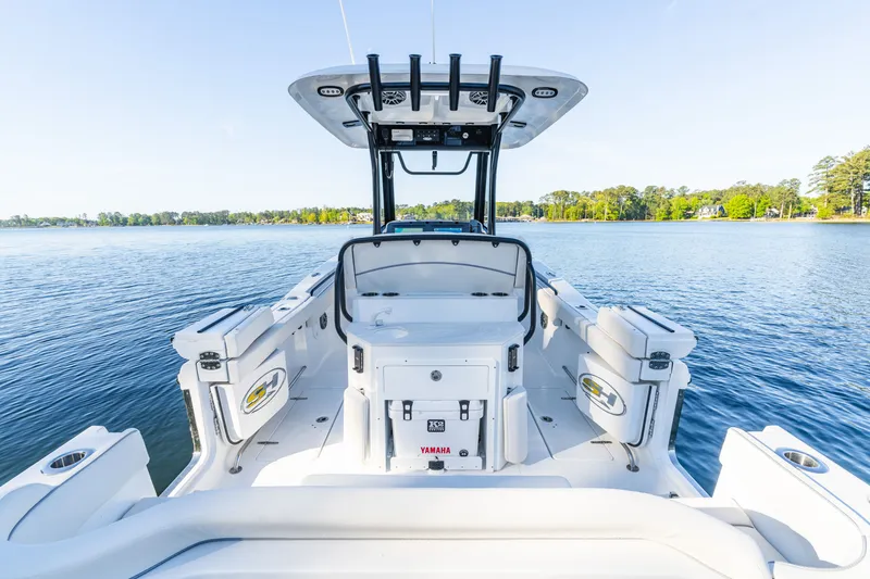 Slide: The Image of 2027 Sea Hunt Ultra 265SE boat on a serene lake, showcasing spacious deck and seating. - 61