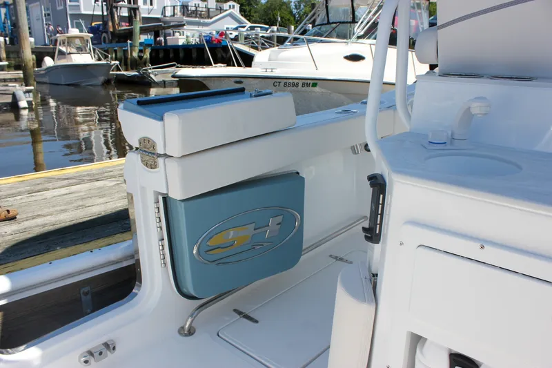 Slide: The Image of 2027 Sea Hunt Ultra 265SE boat interior with storage compartment and docked boats in background. - 9