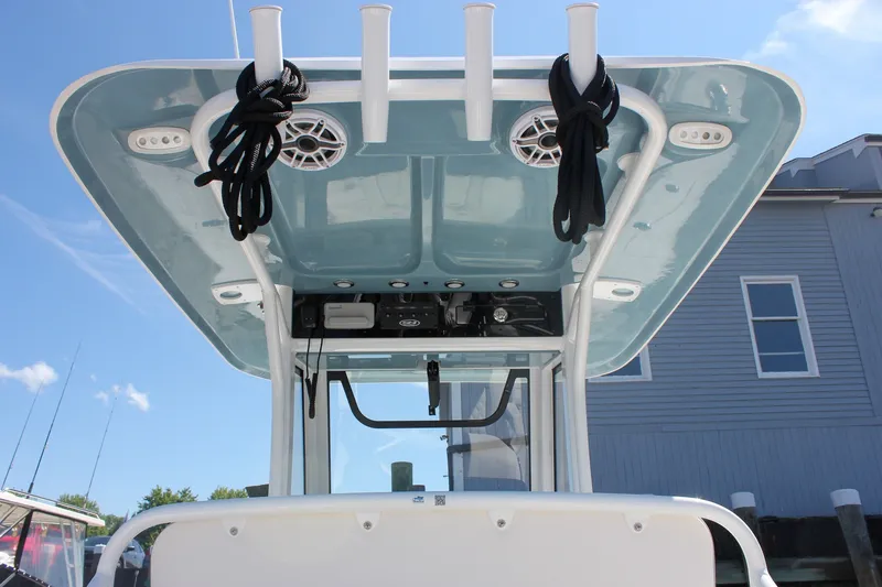 Slide: The Image of 2027 Sea Hunt Ultra 265SE boat with T-top and rod holders, docked under clear sky. - 18