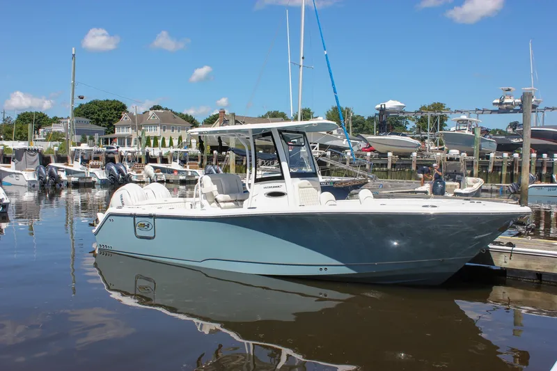 Slide: The Image of 2027 Sea Hunt Ultra 265SE boat docked at a marina under a clear blue sky. - 53