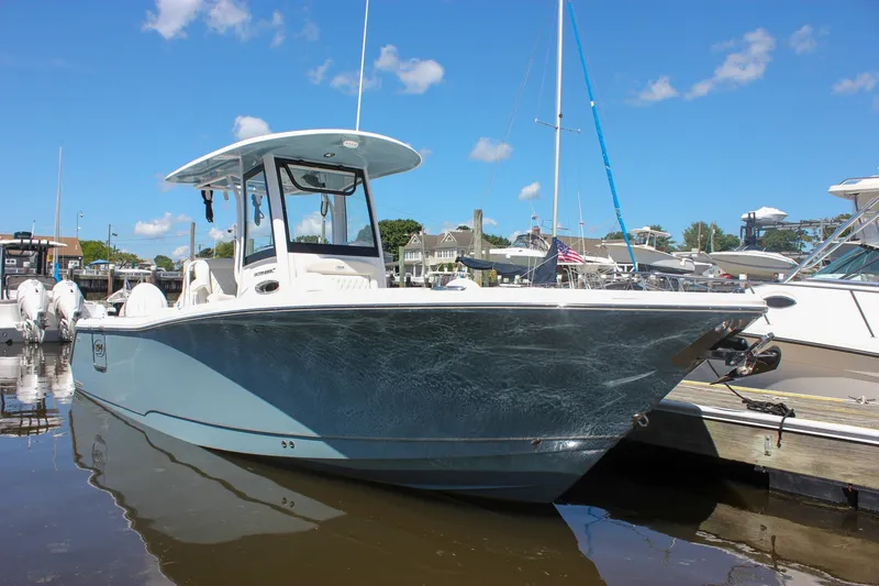 Slide: The Image of 2027 Sea Hunt Ultra 265SE boat docked in a marina under a clear blue sky. - 51