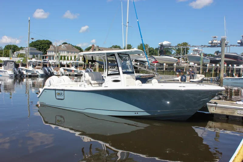 Slide: The Image of 2027 Sea Hunt Ultra 265SE boat docked at a marina under a clear blue sky. - 52