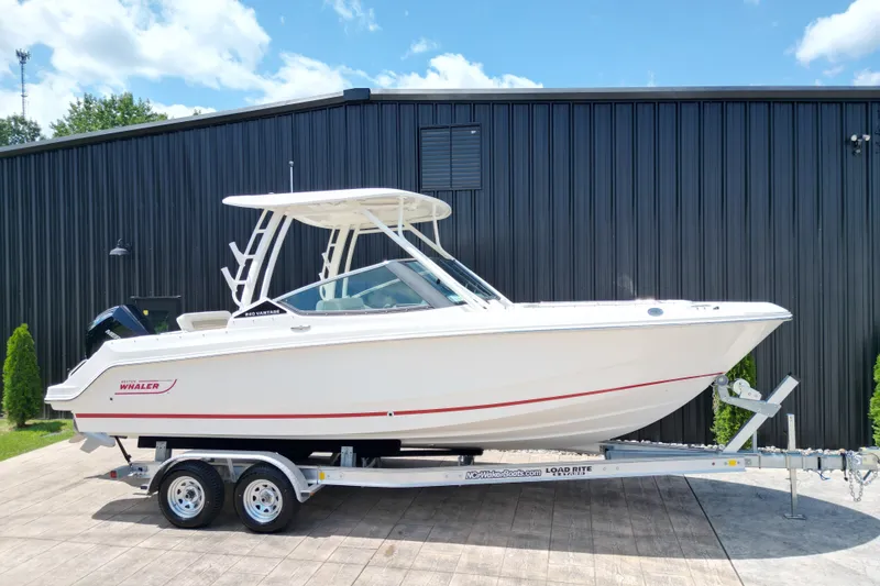 Slide: The Image of 2025 Boston Whaler 240 Vantage boat on trailer, parked outdoors against a black building. - 18