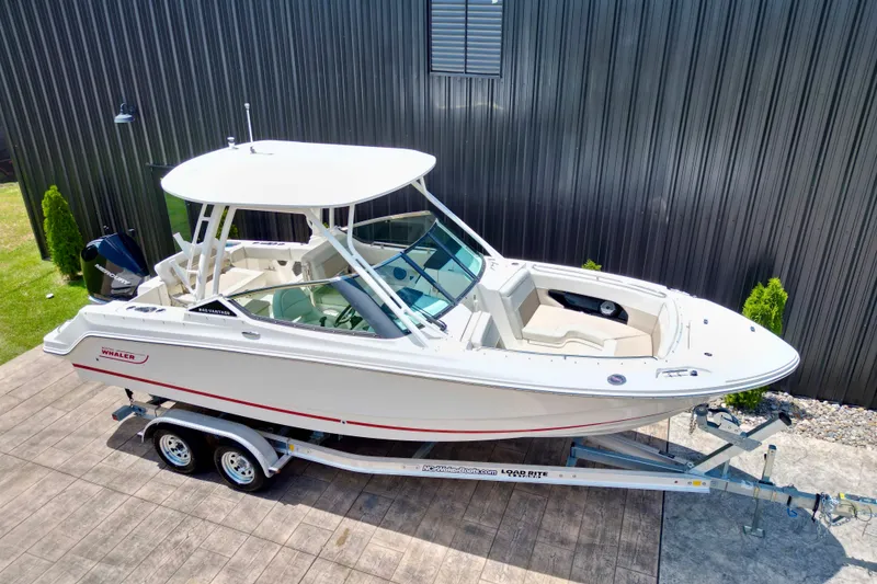 Slide: The Image of 2025 Boston Whaler 240 Vantage boat on trailer, parked outdoors near a metal building. - 3