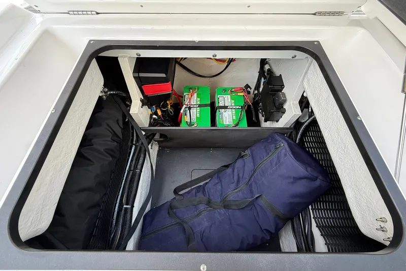 Slide: The Image of Storage compartment of 2027 Monterey Elite 27 OB boat with batteries and a blue bag. - 23