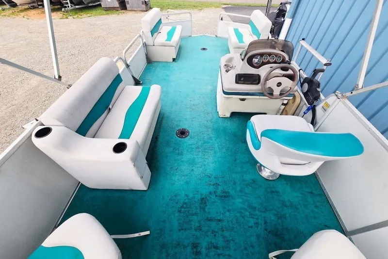 Slide: The Image of 1998 Sun Tracker Fishin' Barge 21 interior with teal and white seating, steering console. - 15