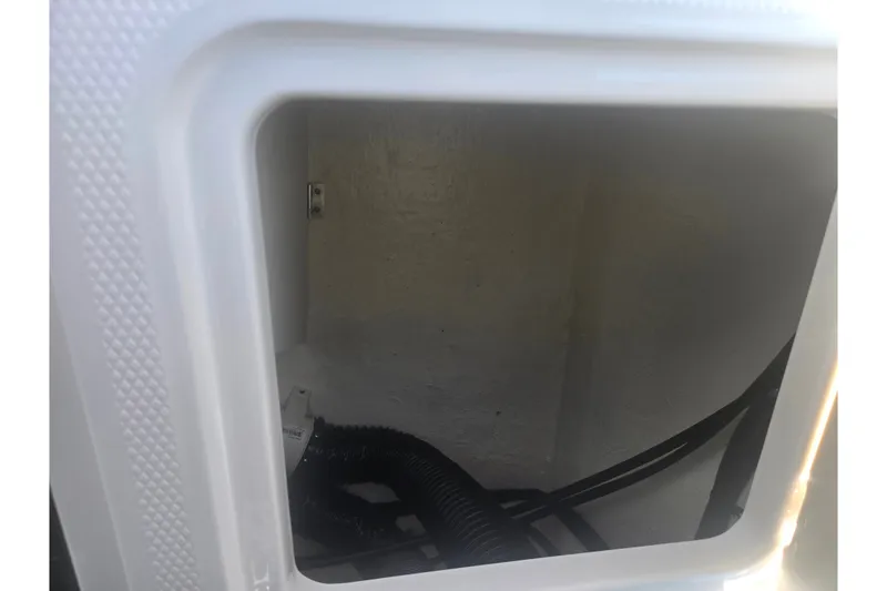 Slide: The Image of Storage compartment of 2023 Chaparral 21 SSi boat, featuring interior wiring and tubing. - 27