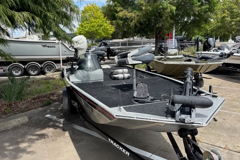 Slide: The Image of 2012 Tracker Pro 165 fishing boat parked outdoors, surrounded by trees and other boats. - 66