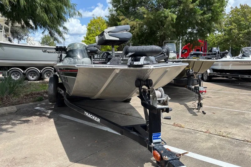 Slide: The Image of 2012 Tracker Pro 165 boat on trailer in parking lot, surrounded by trees and other boats. - 21