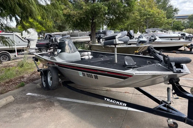 Slide: The Image of 2012 Tracker Pro 165 boat on trailer in parking lot, surrounded by trees and other boats. - 25