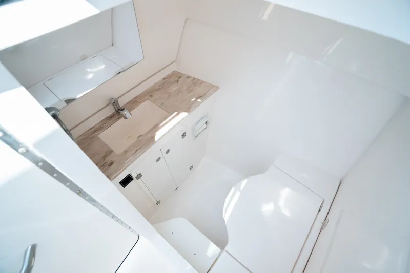 Slide: The Image of Interior of 2018 Pursuit DC 325 Dual Console boat, featuring a compact, modern bathroom. - 25