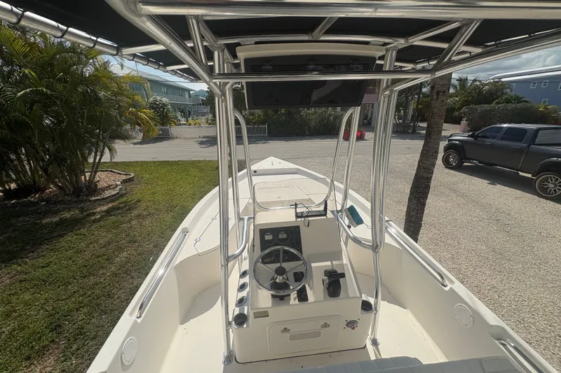 Slide: The Image of 2015 Bulls Bay 2200 boat interior with steering console and T-top, parked outdoors. - 14