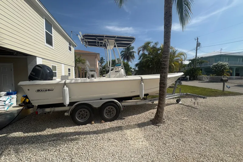 Slide: The Image of 2015 Bulls Bay 2200 boat on trailer beside a house, under a clear blue sky. - 2