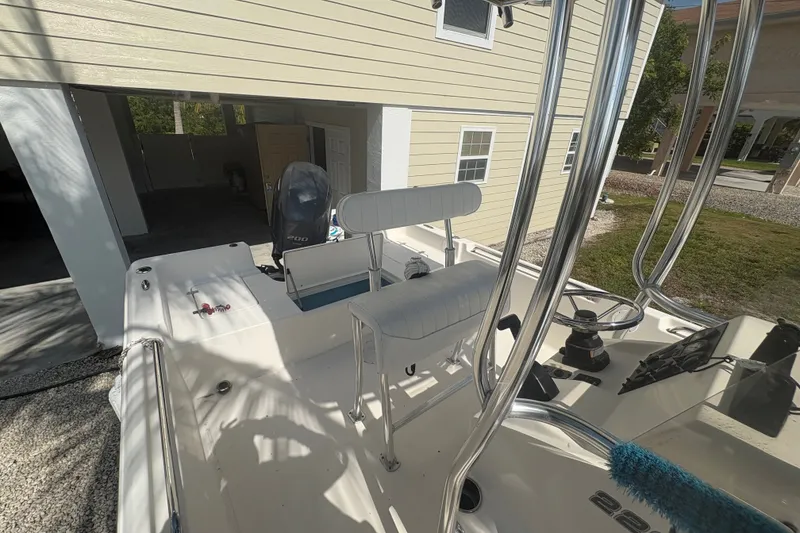Slide: The Image of 2015 Bulls Bay 2200 boat with seating and controls, parked near a house. - 11