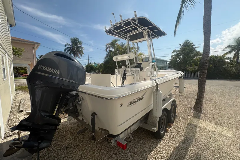 Slide: The Image of 2015 Bulls Bay 2200 boat with Yamaha engine, parked on gravel near palm trees. - 3