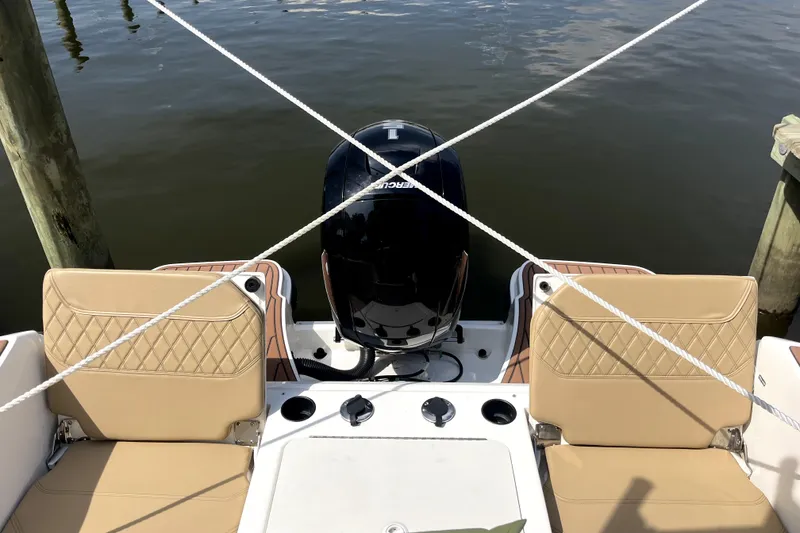Slide: The Image of 2024 Trophy CC22 boat with tan seats and outboard motor, docked on calm water. - 5