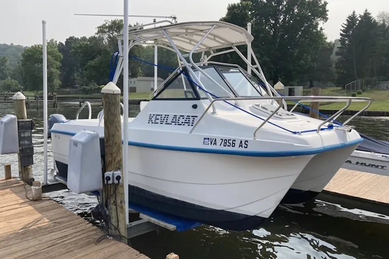 Slide: The Image of 1998 Kevlacat Series 2000 Cuddy Cabin OB docked by a serene lakeside. - 2