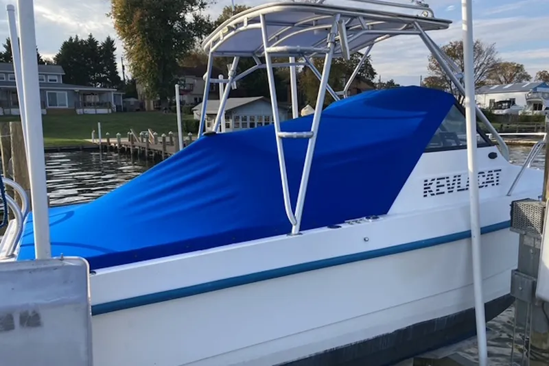 Slide: The Image of 1998 Kevlacat Series 2000 Cuddy Cabin OB with blue cover docked by waterfront homes. - 7