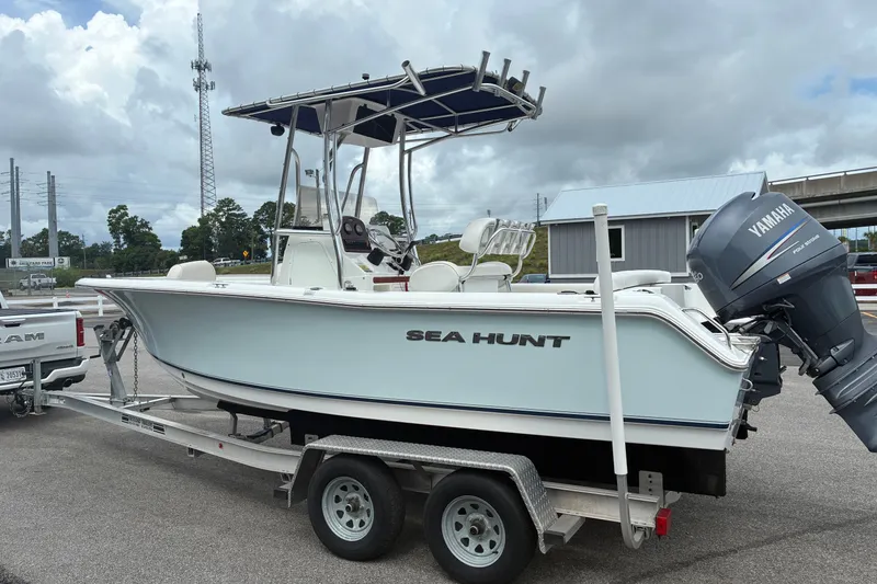 Slide: The Image of 2012 Sea Hunt Ultra 211 boat on trailer with Yamaha outboard motor, parked outdoors. - 17