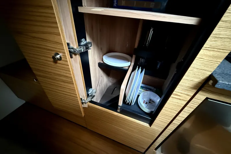 Slide: The Image of Open wooden cabinet with plates inside on a 2024 Boston Whaler 405 Conquest. - 19
