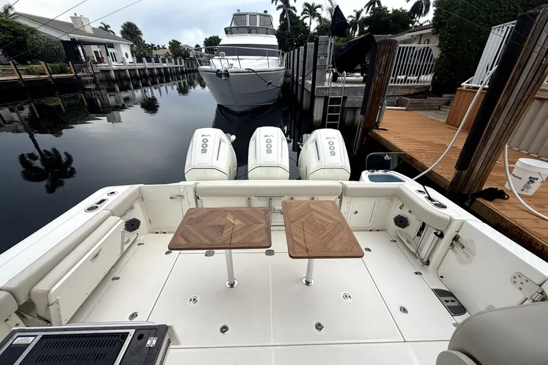 Slide: The Image of 2024 Boston Whaler 405 Conquest boat docked, featuring triple outboard engines and a spacious deck. - 23