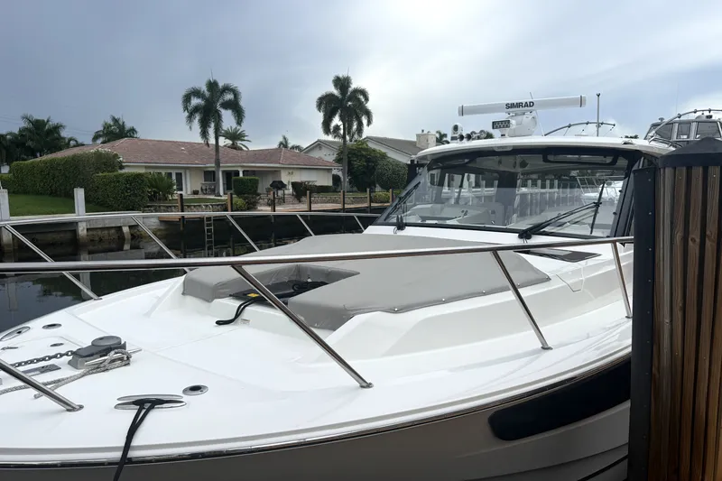 Slide: The Image of 2024 Boston Whaler 405 Conquest docked near waterfront homes with palm trees. - 2