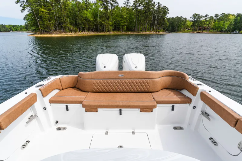 Slide: The Image of 2026 Sea Hunt Ultra 305SE boat with tan seating, on a serene lake near a wooded island. - 25