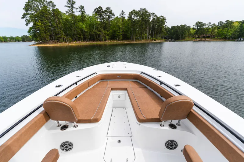 Slide: The Image of 2026 Sea Hunt Ultra 305SE boat with tan seating, on a serene lake near a wooded island. - 9