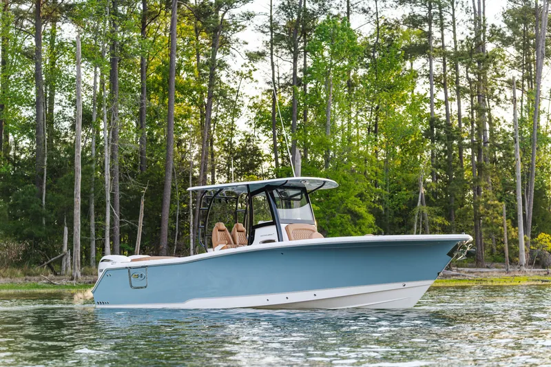 Slide: The Image of 2026 Sea Hunt Ultra 305SE boat on calm water, surrounded by lush trees. - 19
