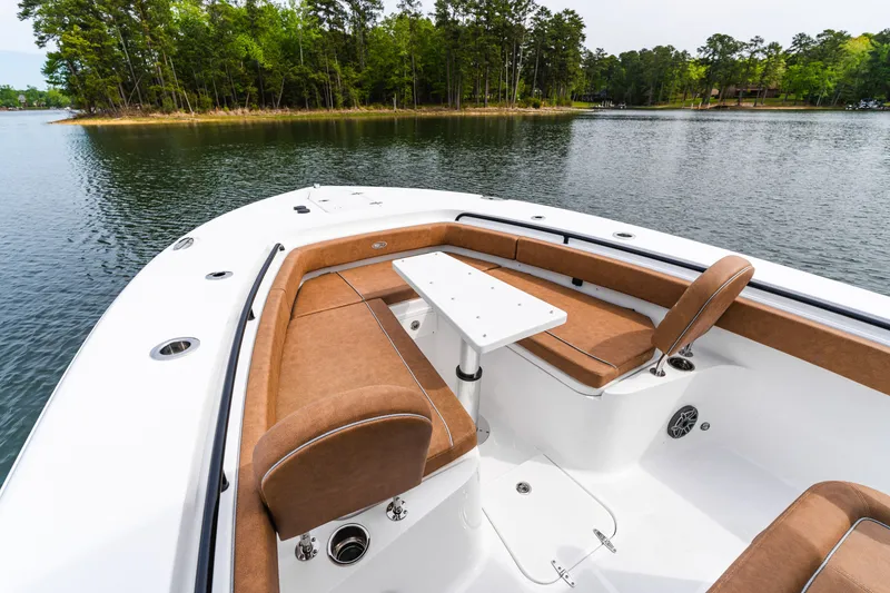 Slide: The Image of 2026 Sea Hunt Ultra 305SE boat with brown seating, white table, and scenic lake view. - 8